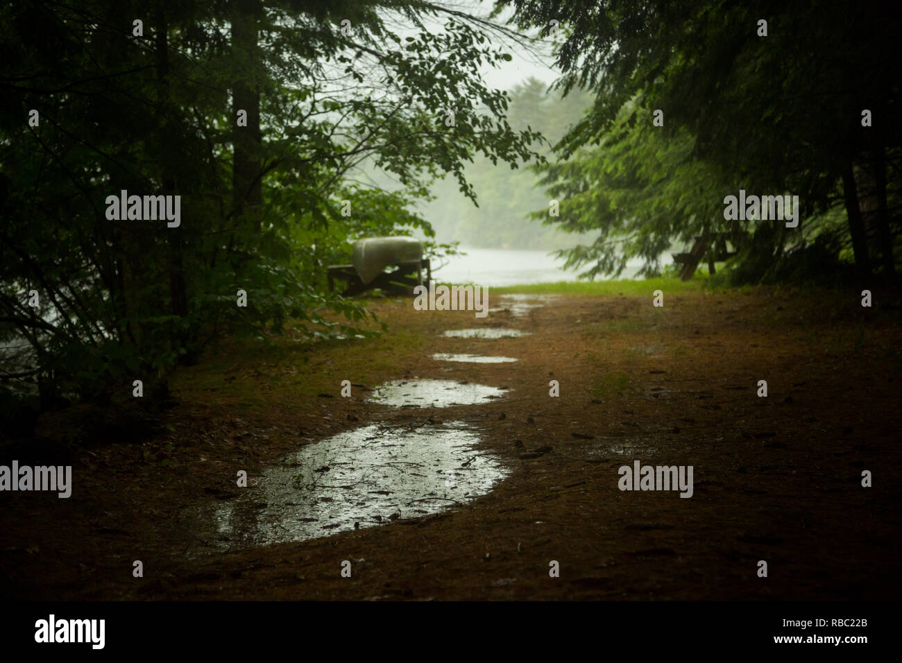 Un canoë attend par le lac un jour de pluie. Banque D'Images Un canoë attend par le lac un jour de pluie. Banque D'Images