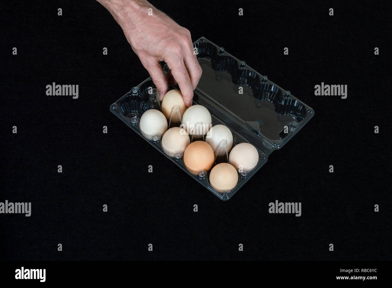 La main des hommes en tenant un oeuf de l'oeuf en plastique fort sur fond de feutre noir. Banque D'Images