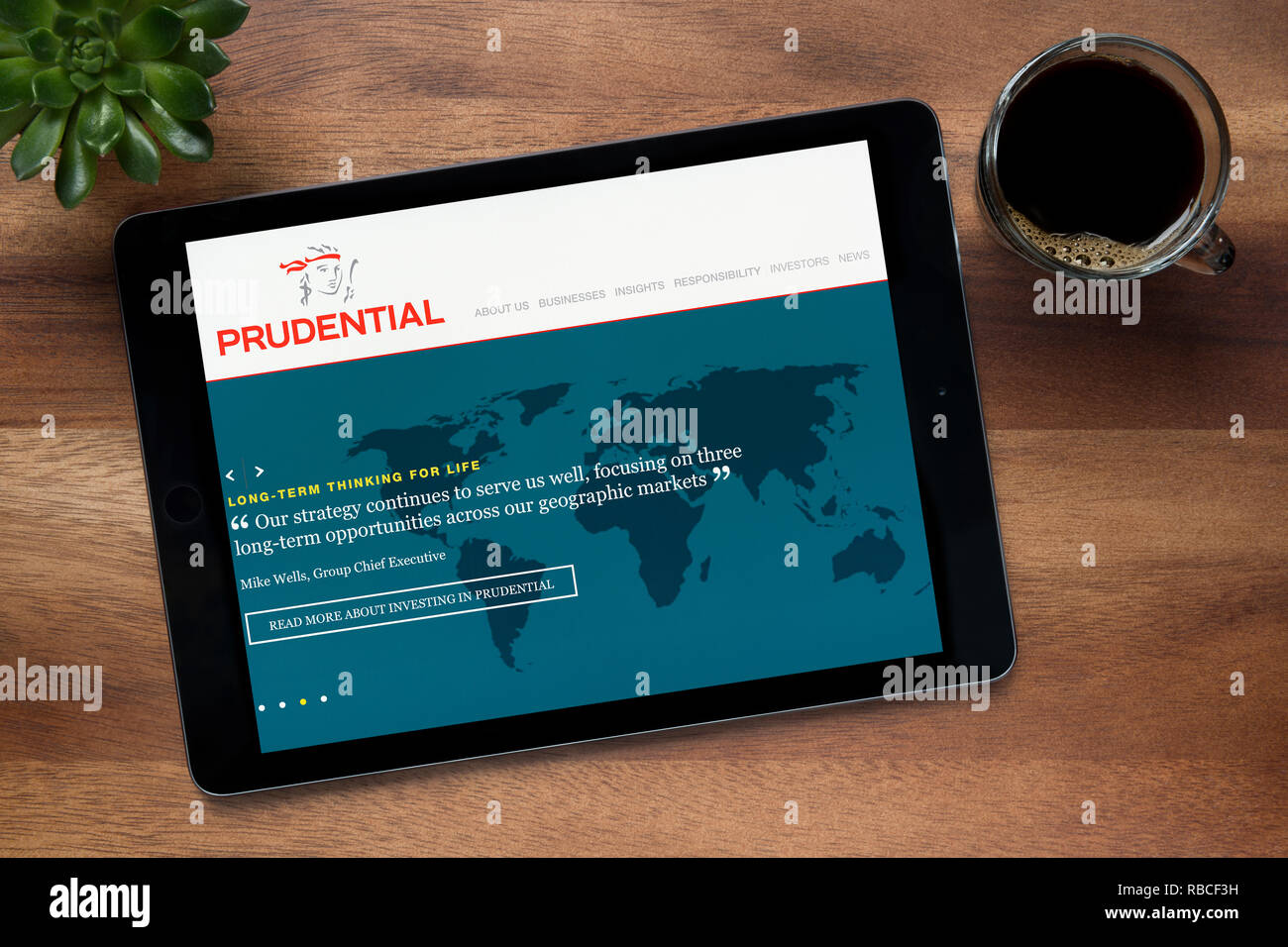 Le site web de Prudential est vu sur un iPad tablet, sur une table en bois avec une machine à expresso et d'une plante (usage éditorial uniquement). Banque D'Images