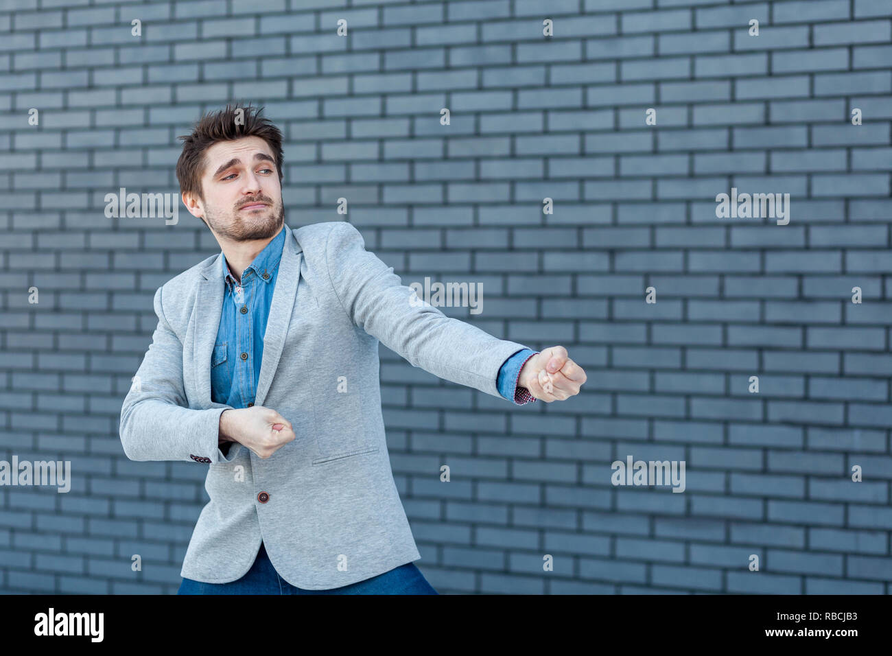 Beau Portrait d'homme barbu sérieux dans un style décontracté et permanent de faire tirer geste. Piscine studio shot sur mur de brique arrière-plan. Banque D'Images