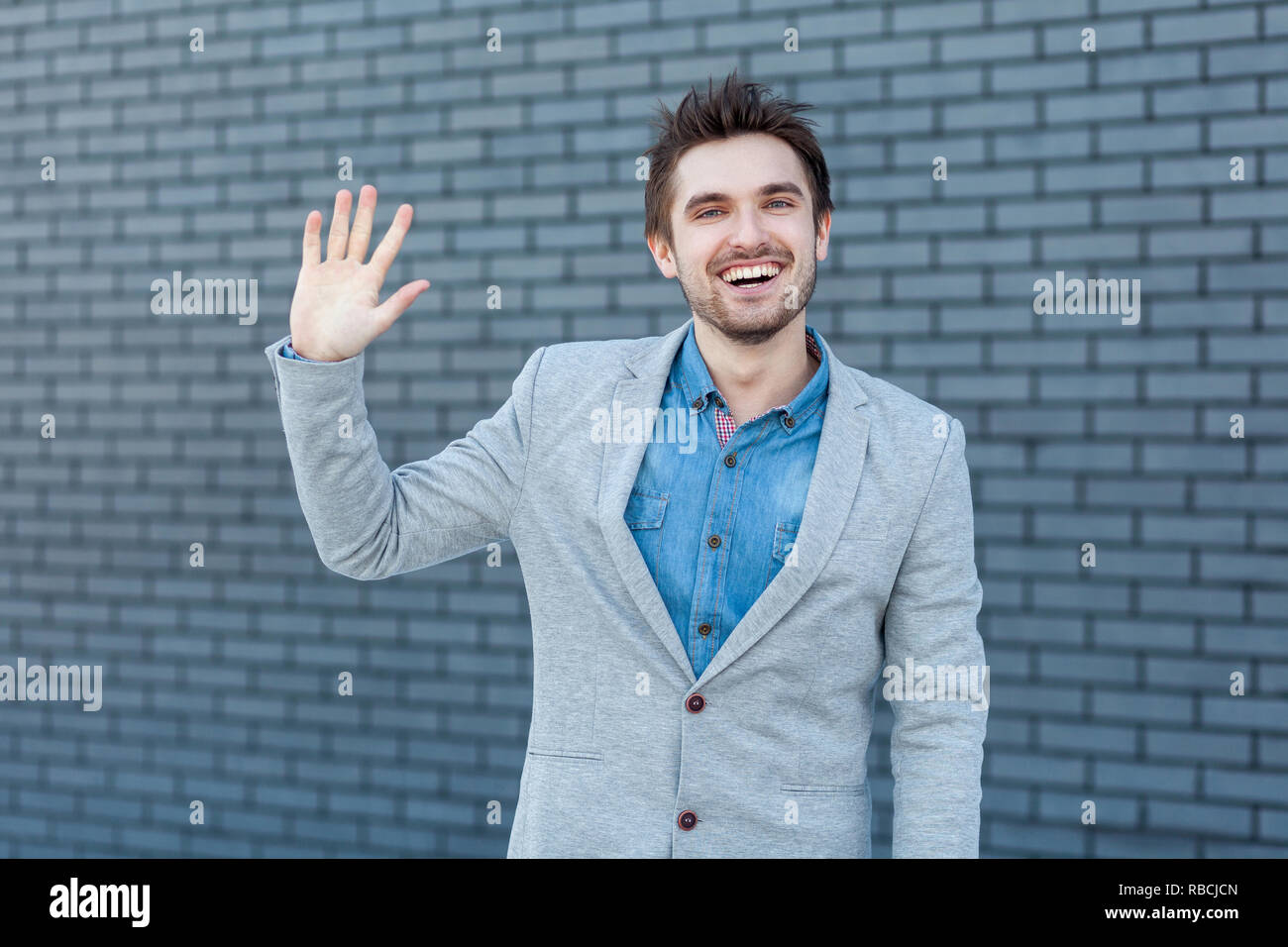 Bonjour, soyez le bienvenu. Portrait of happy beau barbu dans un style décontracté et permanent à la caméra à souhaits avec geste et souriant à pleines dents. je Banque D'Images