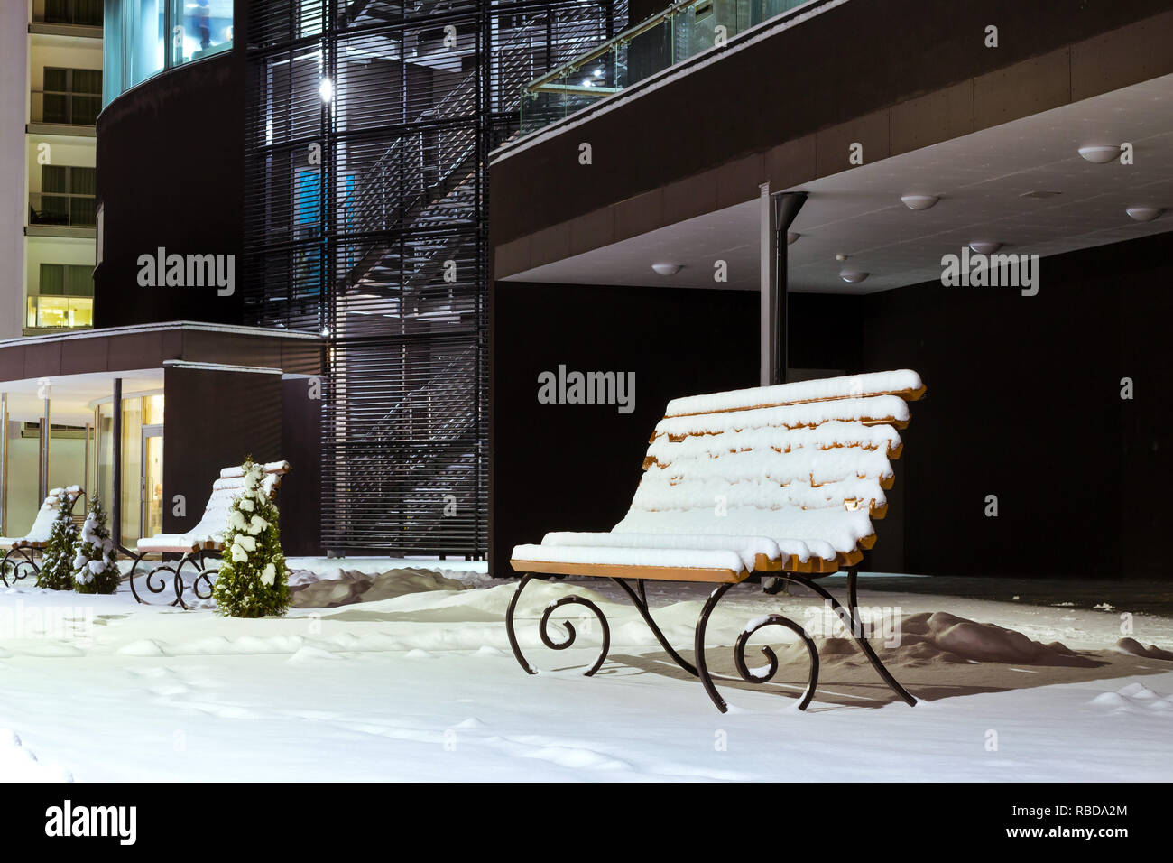 Bâtiment moderne fait de verre et de béton au milieu de l'hiver neige paysage de nuit. Le Nord de l'hiver sévère et temps de neige. Des bancs en bois couverte de neige. Narva-Joesuu Banque D'Images