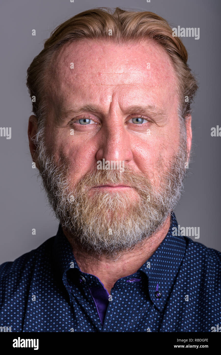 Visage d'homme barbu d'âge mûr en arrière-plan gris Banque D'Images