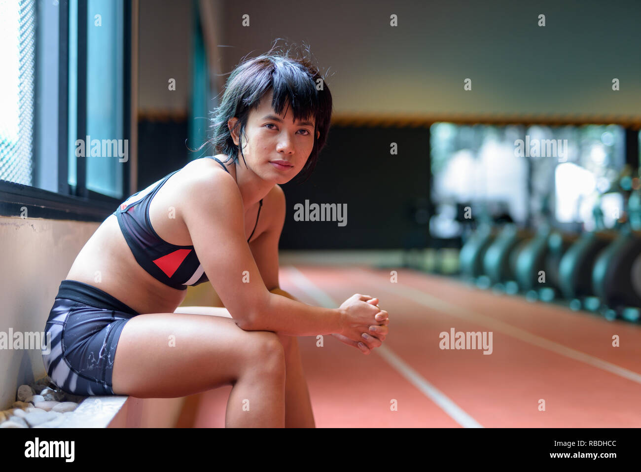 Belle jeune femme asiatique assis et se détendre à la salle de sport Banque D'Images