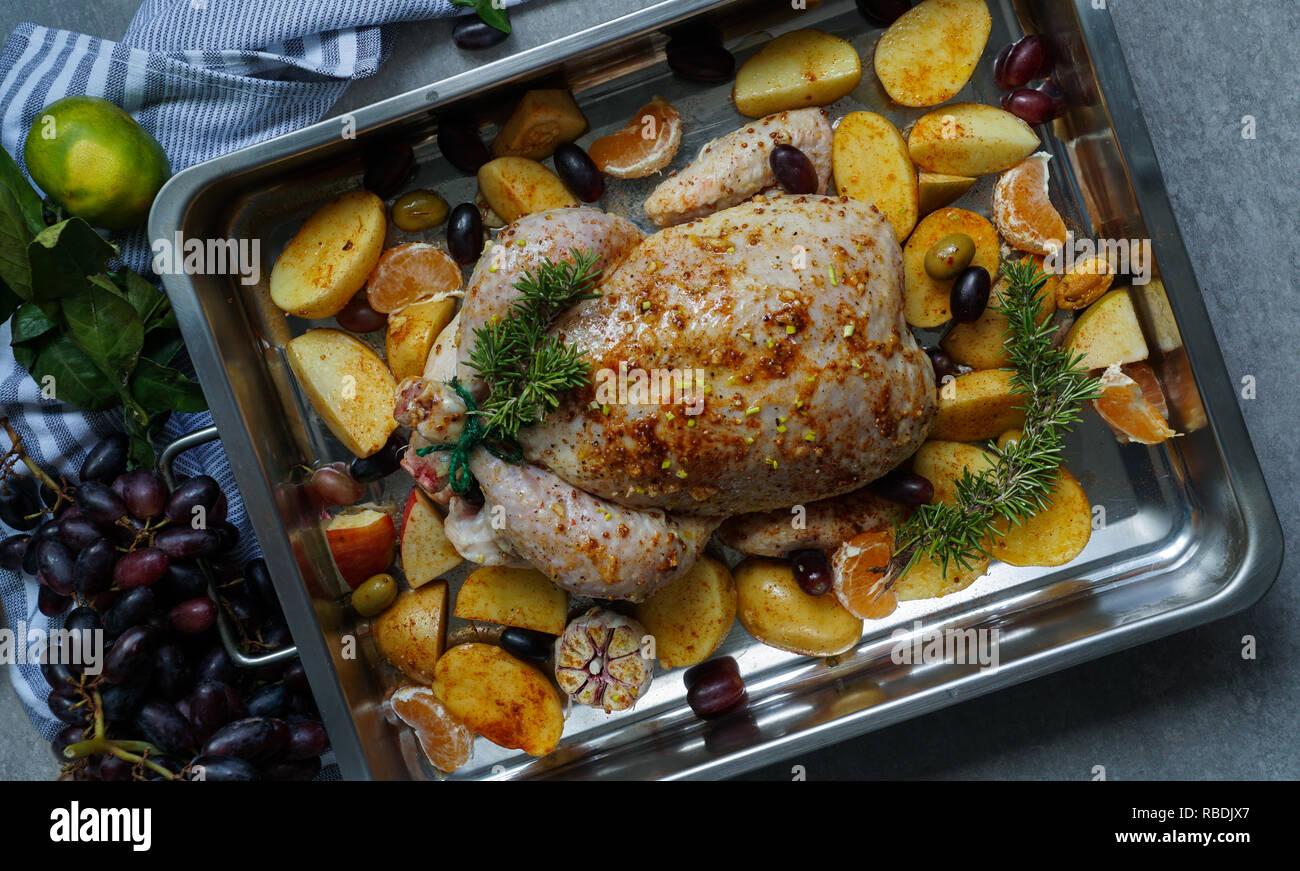 La Turquie ou poulet cuit au four avec la peau croustillante d'or avec des raisins et des pommes de terre, la mandarine. Poulet rôti dans le plat de cuisson. Dîner de Noël. Mise à plat. Vue d'en haut Banque D'Images