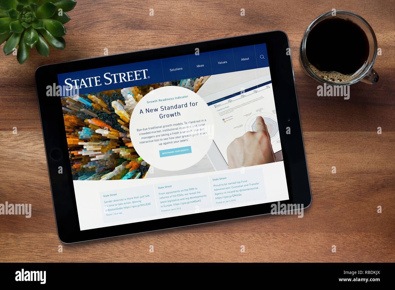 Le site web de State Street est vu sur un iPad tablet, sur une table en bois avec une machine à expresso et d'une plante (usage éditorial uniquement). Banque D'Images Le site web de State Street est vu sur un iPad tablet, sur une table en bois avec une machine à expresso et d'une plante (usage éditorial uniquement). Banque D'Images