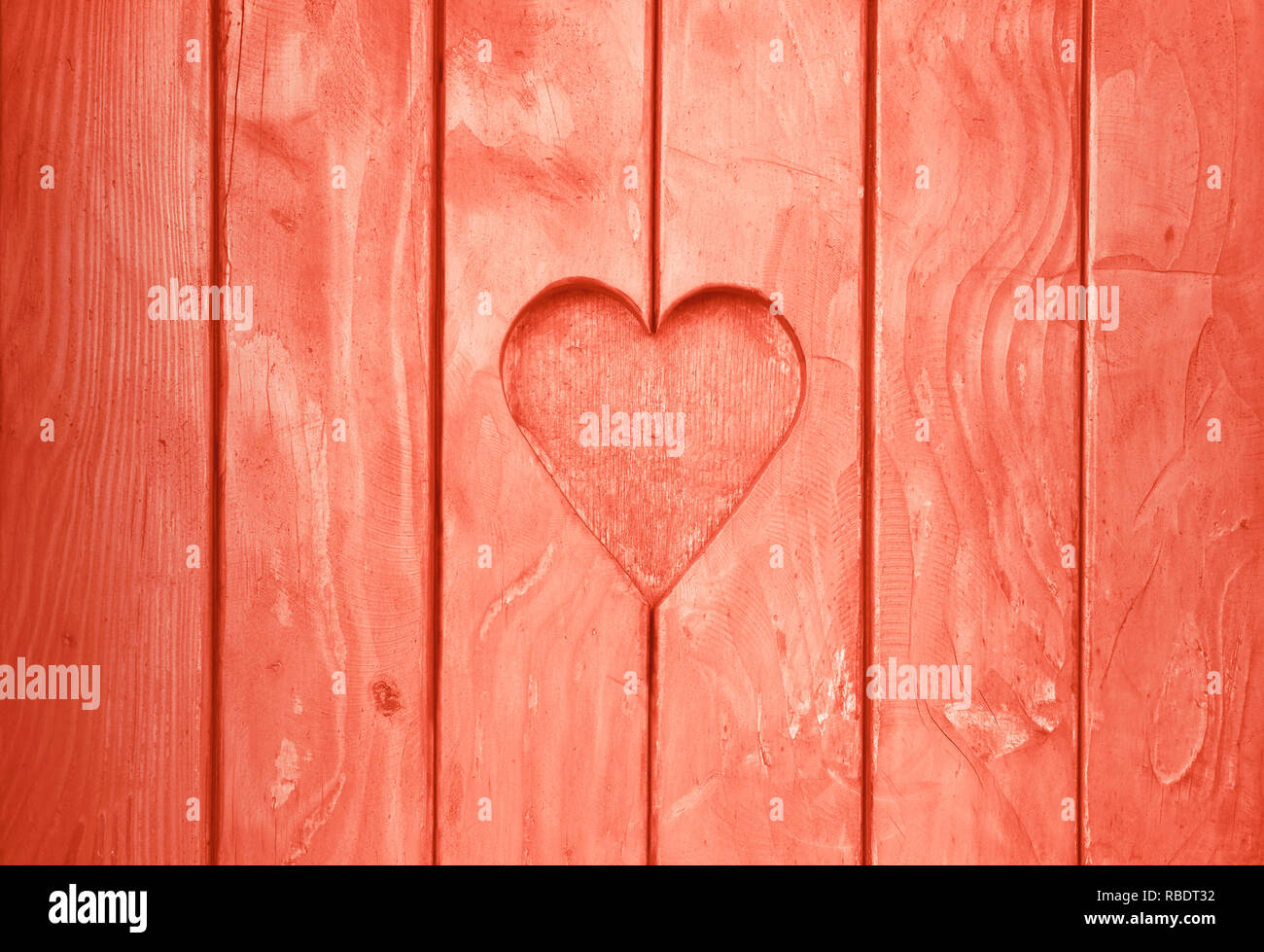 Près d'une forme de coeur, symbole de l'amour et de romance, sculpté en bois coupé en planches en bois texture background rose corail, volets peints Banque D'Images