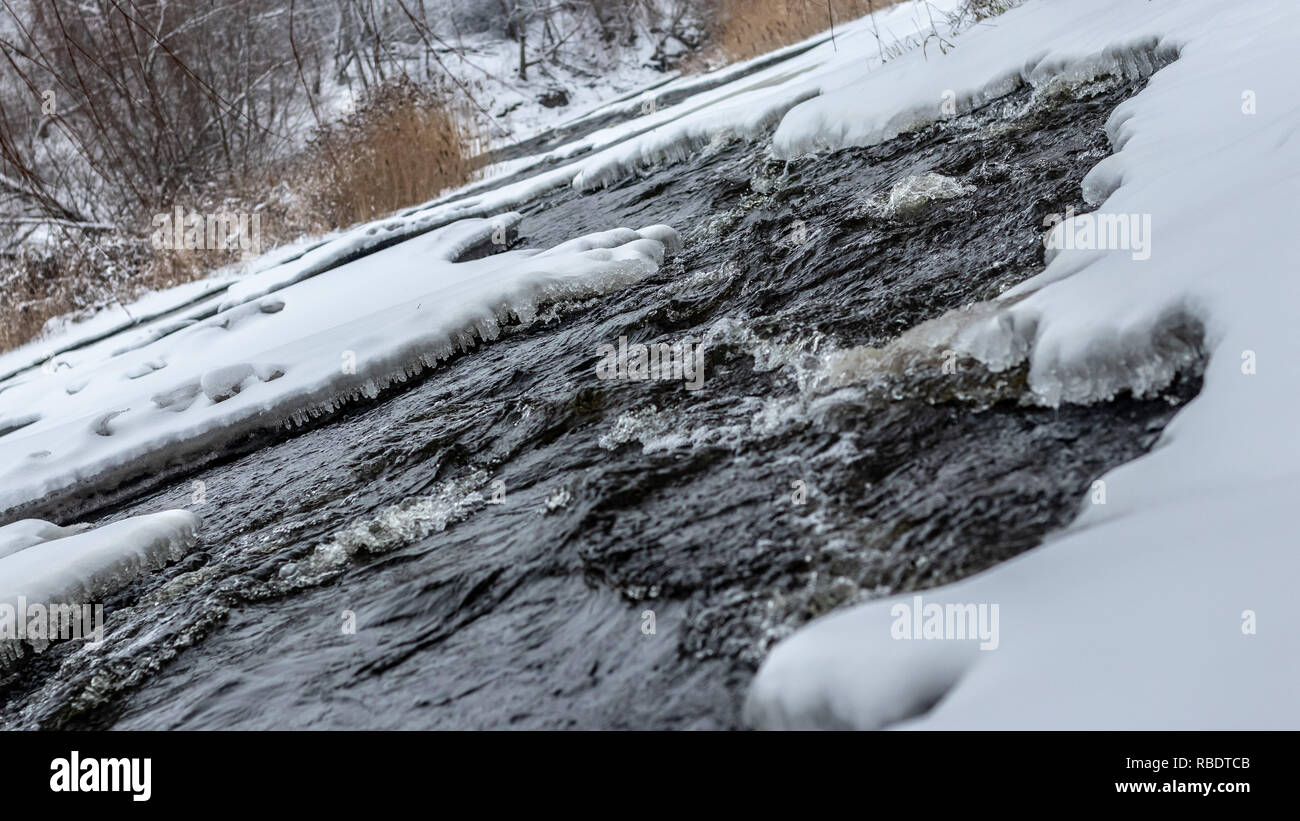 Rivière gelée avec une belle fusion de l'eau froide sous l'plaques de glace Banque D'Images