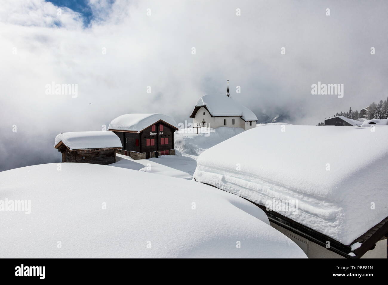 Refuges de montagne couverte de neige et église entourée de nuages Bettmeralp Française, canton du Valais Suisse Europe Banque D'Images