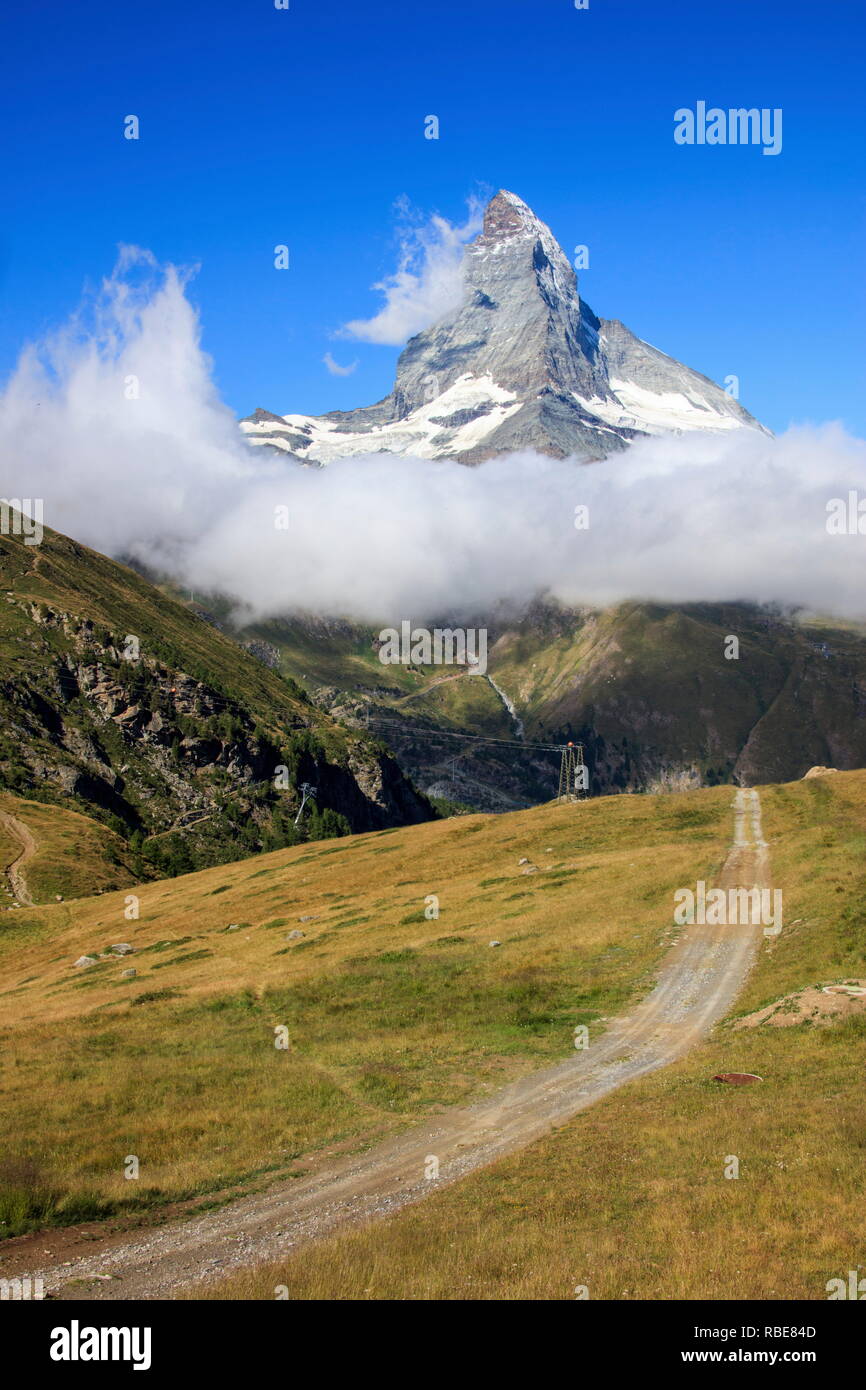 Un chemin parmi les vertes prairies montre le Cervin encadrée par les nuages et ciel bleu en été Gornergrat Valais Suisse Europe Banque D'Images