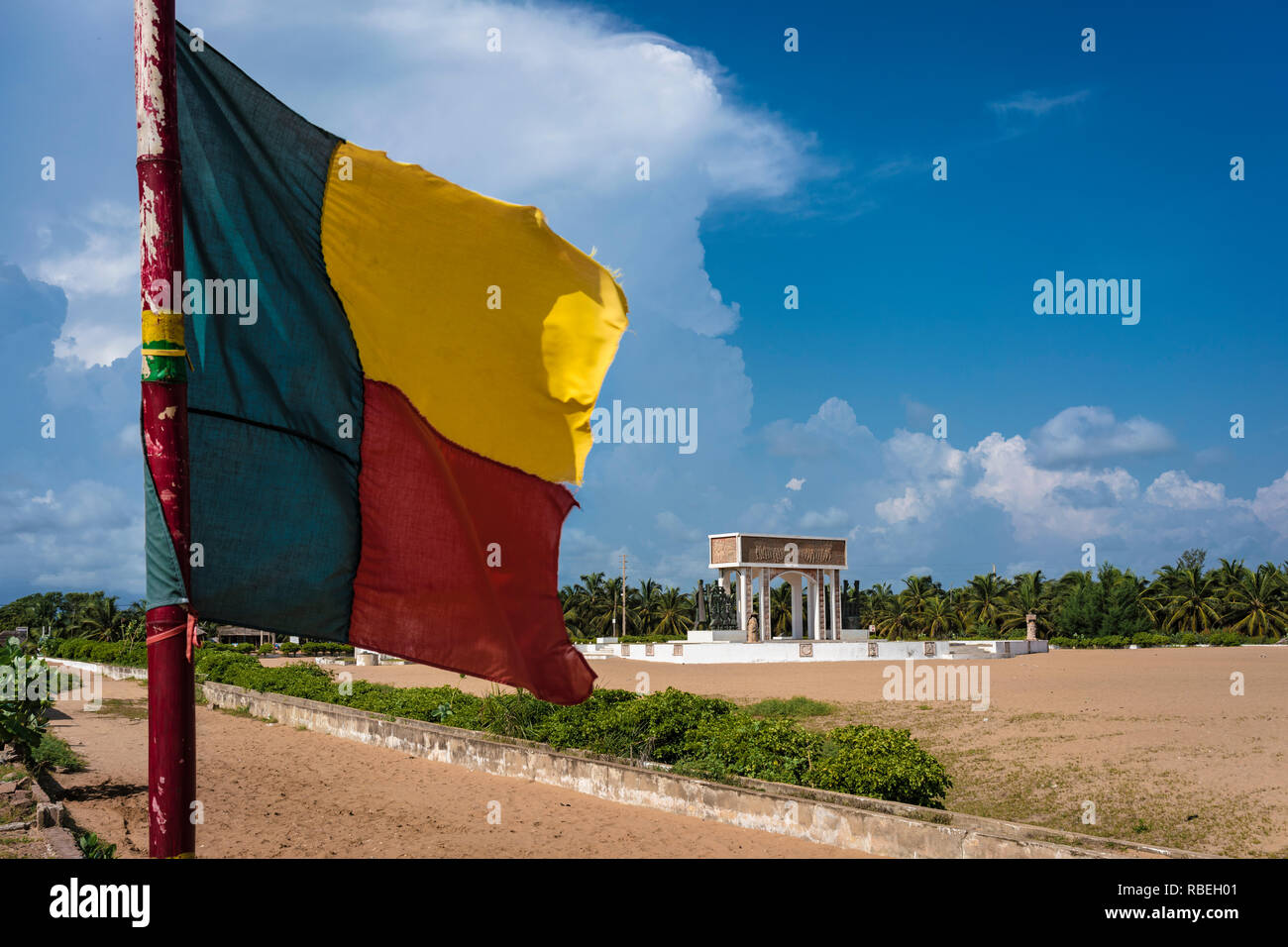 Le drapeau béninois en premier plan avec la porte de non retour (Porte du non retour) à Ouidah en arrière-plan, un ancien esclave trade post au Bénin. Banque D'Images