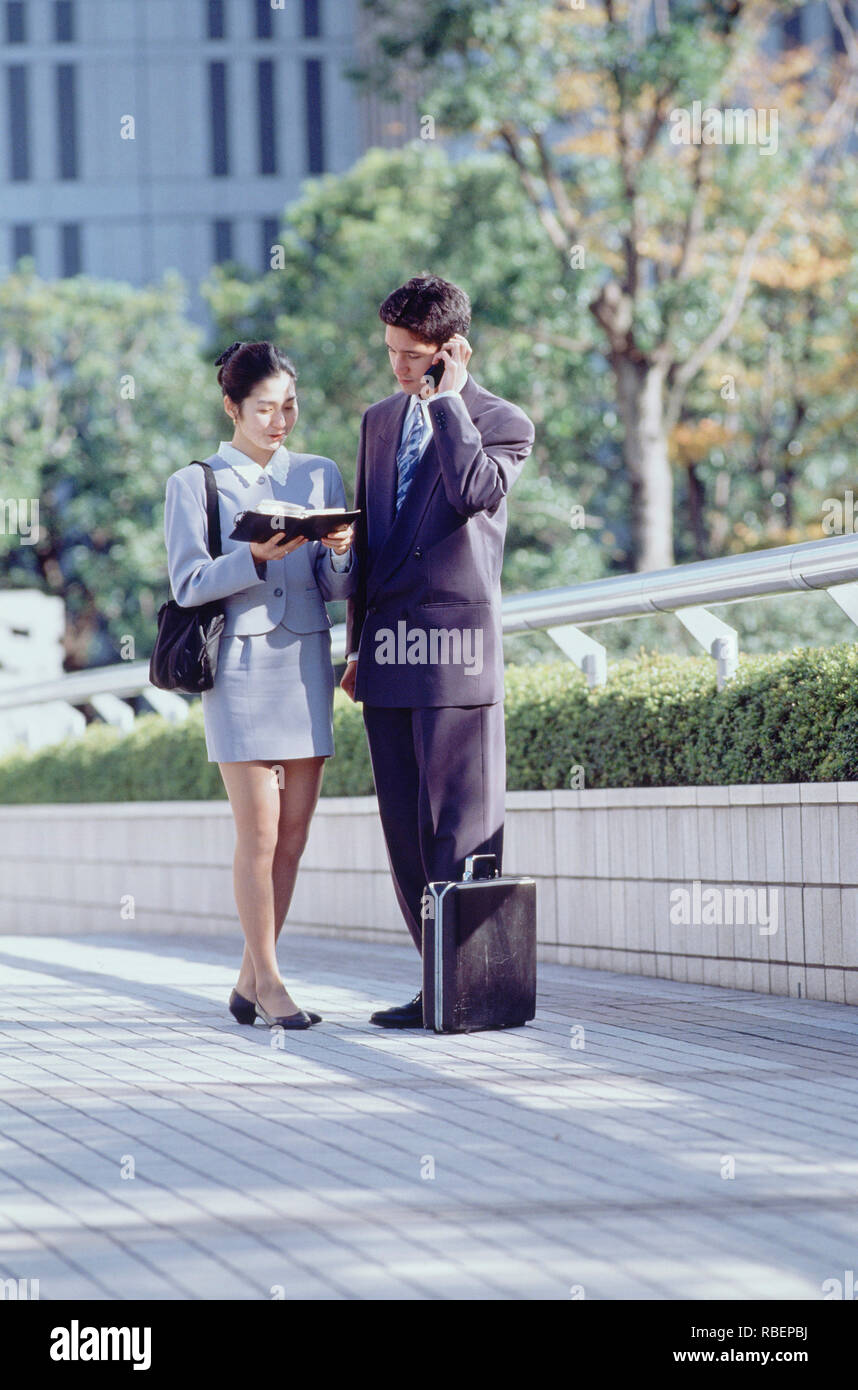 Japon. Tokyo. Hommes et femmes cadres debout à l'extérieur de la ville. Banque D'Images