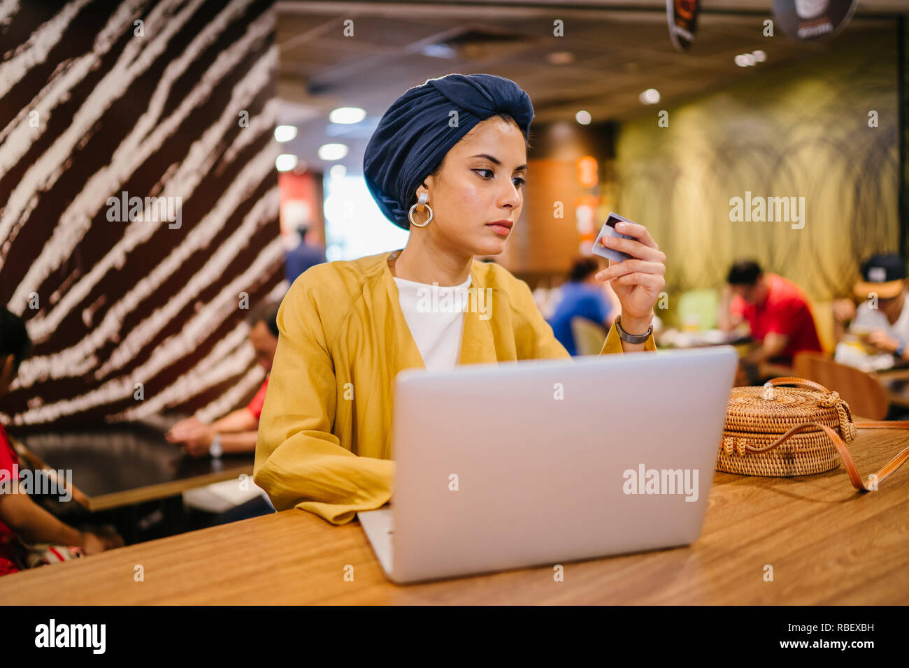 Portrait d'une jeune et belle femme musulmane malaise portant un turban de payer pour ses achats en ligne en ligne avec une carte de crédit sur son portable. Banque D'Images
