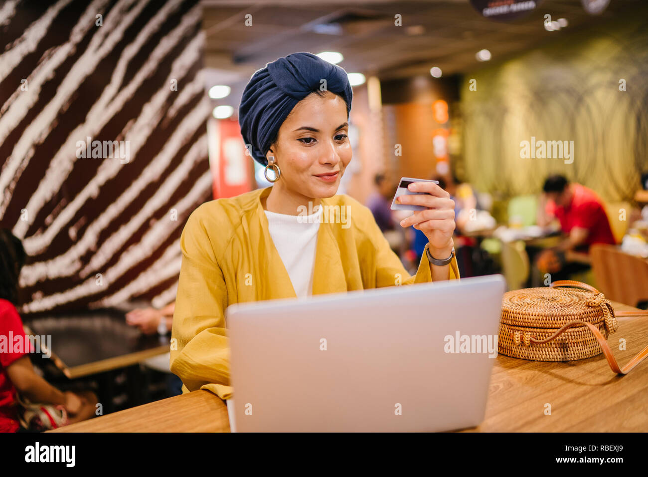 Portrait d'une jeune et belle femme musulmane malaise portant un turban de payer pour ses achats en ligne en ligne avec une carte de crédit sur son portable. Banque D'Images