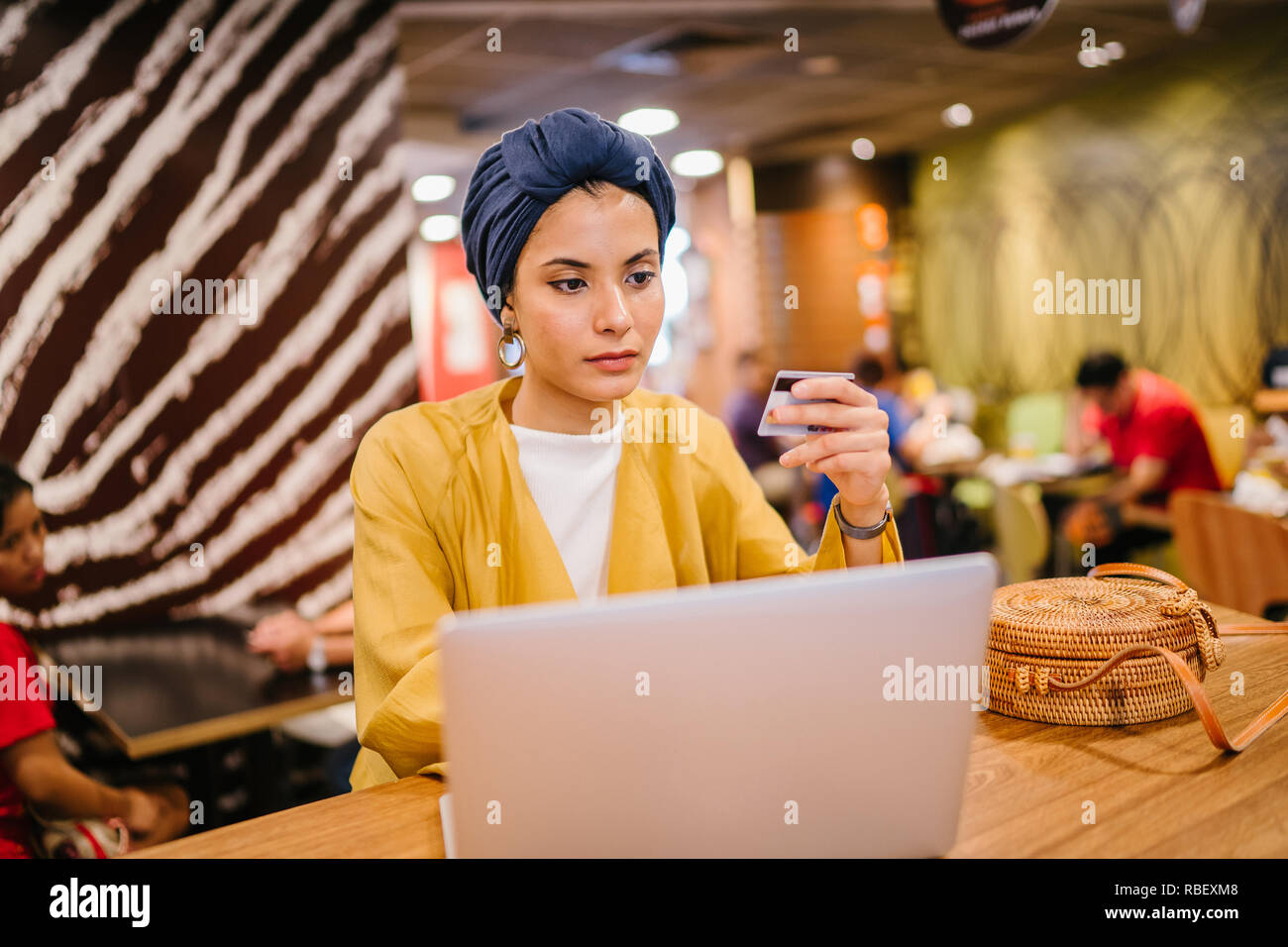 Portrait d'une jeune et belle femme musulmane malaise portant un turban de payer pour ses achats en ligne en ligne avec une carte de crédit sur son portable. Banque D'Images