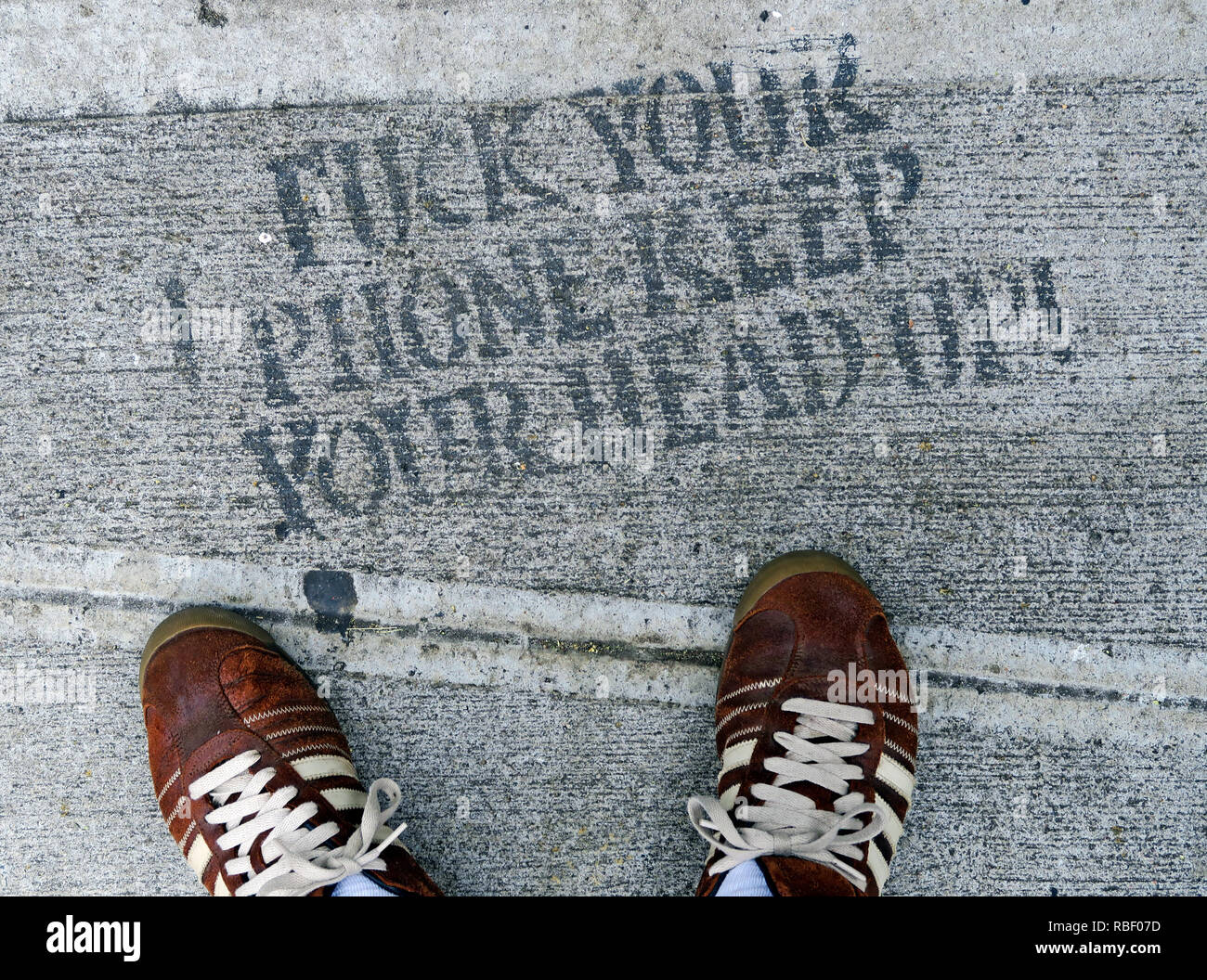 Fuck Your Phone, garder la tête haute, le pochoir, la chaussée avec pieds en formateurs Adidas, Chinatown, New York City, New York, NY, USA Banque D'Images
