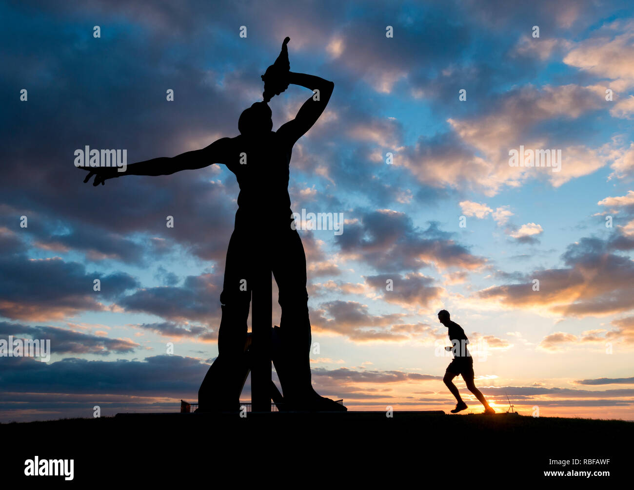 Las Palmas, Gran Canaria, Îles Canaries, Espagne. 10 janvier 2019. Météo : un jogger out pour un lever courir près de l'immense sculpture de Dieu grec Triton ( fils de Poséidon et Amphitrite ), qui domine l'une des plages de la ville de Las Palmas, la capitale de Gran Canaria. Credit : ALAN DAWSON/Alamy Live News Banque D'Images