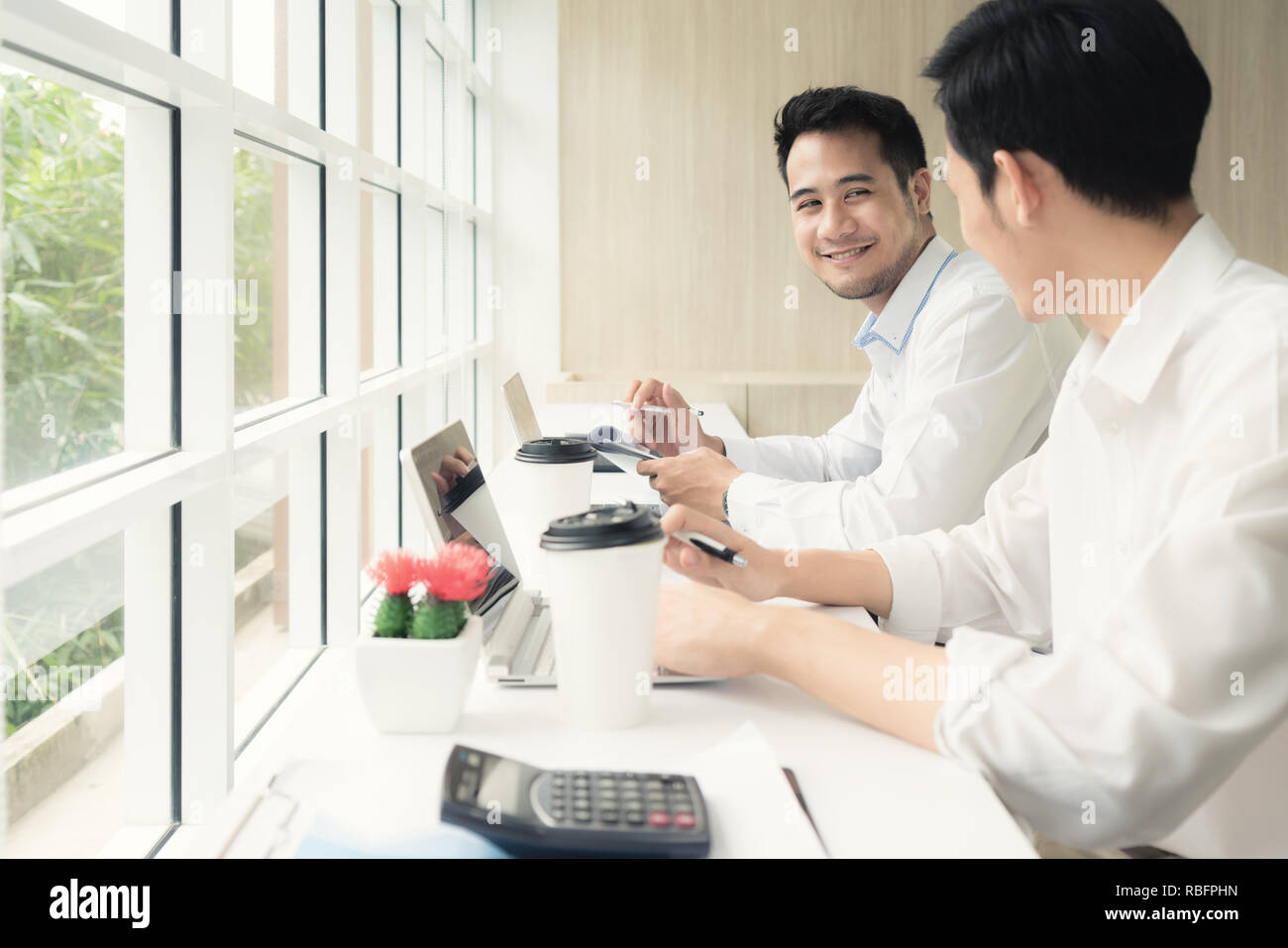 Deux hommes d'Asie assis dans un café et discuter de projet d'entreprise. Deux employés masculins consulting dans le café. Banque D'Images