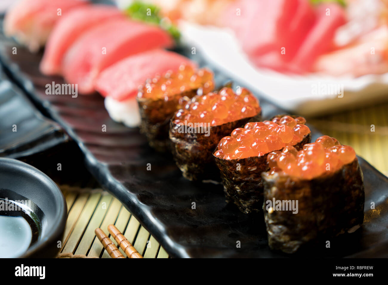 Sushi avec des baguettes et de la sauce de soja. Sushi roll Japanese food in restaurant. Sushi oeufs de saumon avec saumon, légumes, oeufs de poisson volant et de caviar Banque D'Images