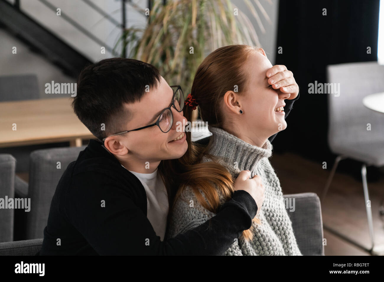Belle surprise couple romantique dans le café. L'homme est couvrant les yeux de sa petite amie pendant qu'elle en attente d'une surprise Banque D'Images