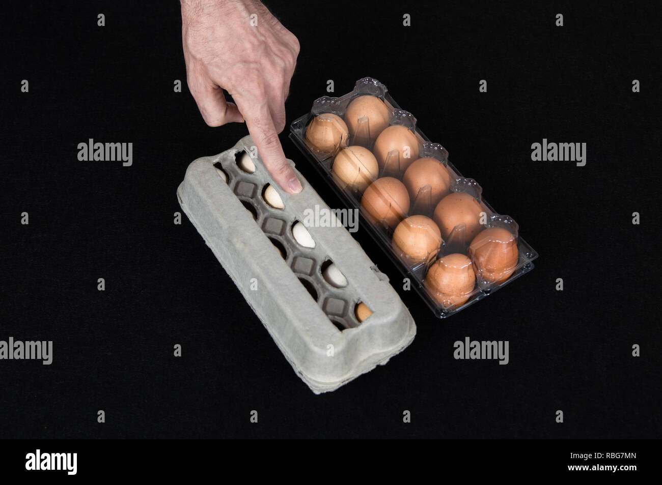 Homme de main montrant un oeuf carton fort au lieu de boîte en plastique plein d'œufs de poule sur fond de feutre noir. Banque D'Images