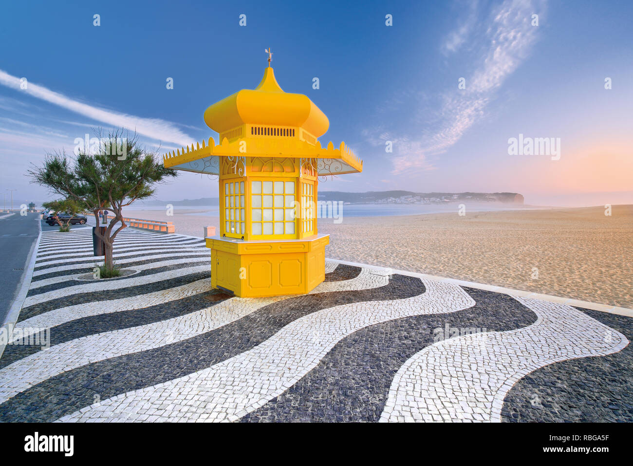 Kiosque jaune sur les trottoirs pavés de noir et de blanc à l'ornement de large plage de sable solitaires Banque D'Images