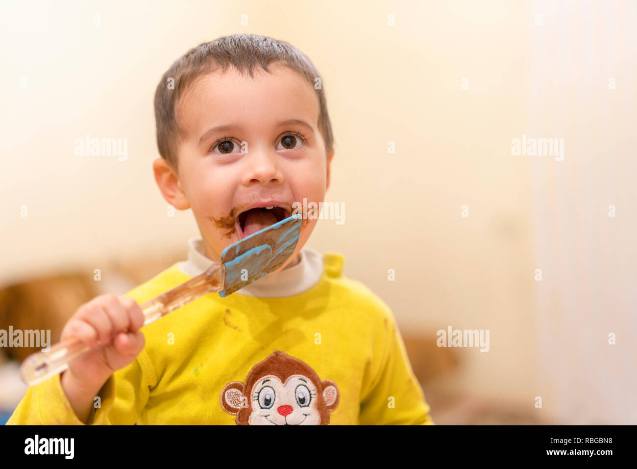 Heureux l'enfant lèche une cuillère de chocolat. Garçon heureux de manger  un gâteau au chocolat. Funny baby eating chocolat avec une cuillère Photo  Stock - Alamy