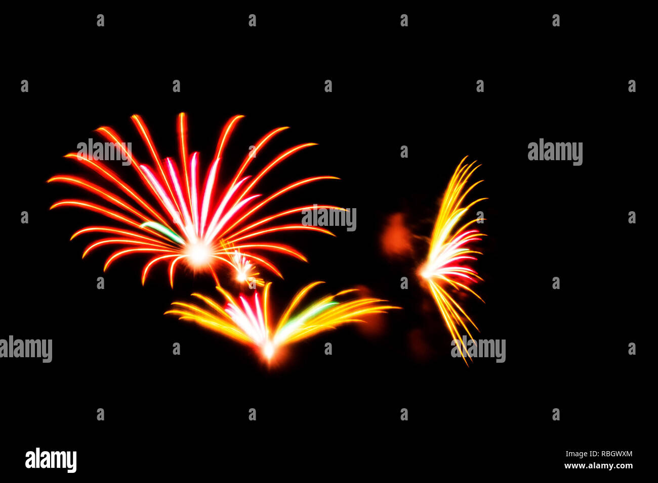 Orange, rose et jaune d'artifice illuminent le ciel sur une sombre nuit après un concert dans un parc. Banque D'Images