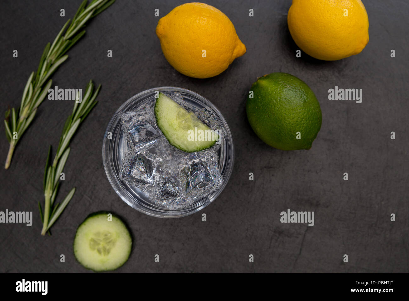 Cocktail gin tonic verre verre avec de la glace au citron lime concombre fond sombre Banque D'Images