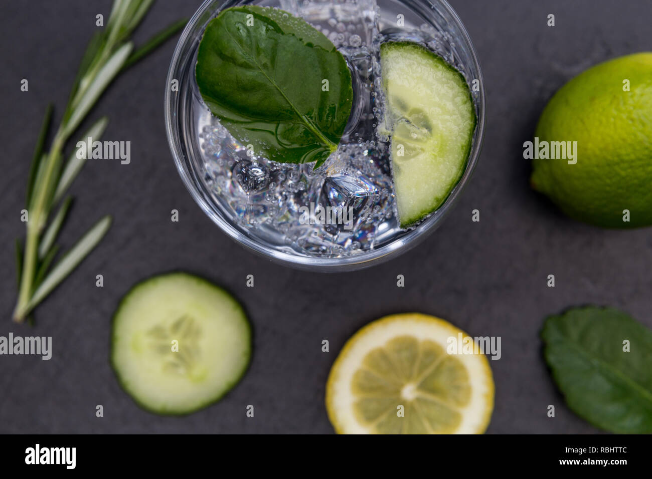 Cocktail gin tonic verre verre avec de la glace au citron lime concombre fond sombre Banque D'Images