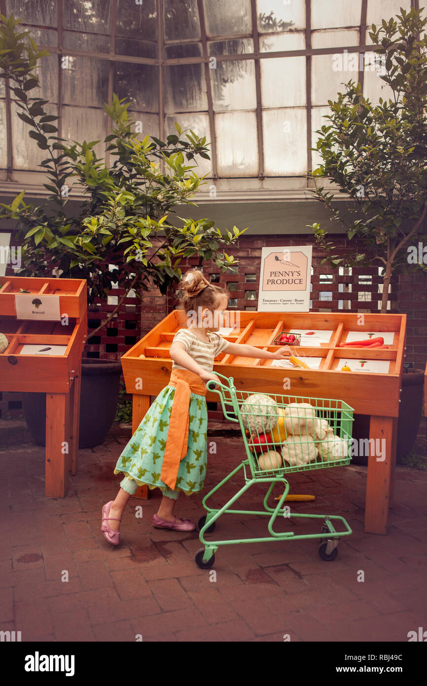 Jeune fille prétendre faire les courses de fruits et légumes Banque D'Images