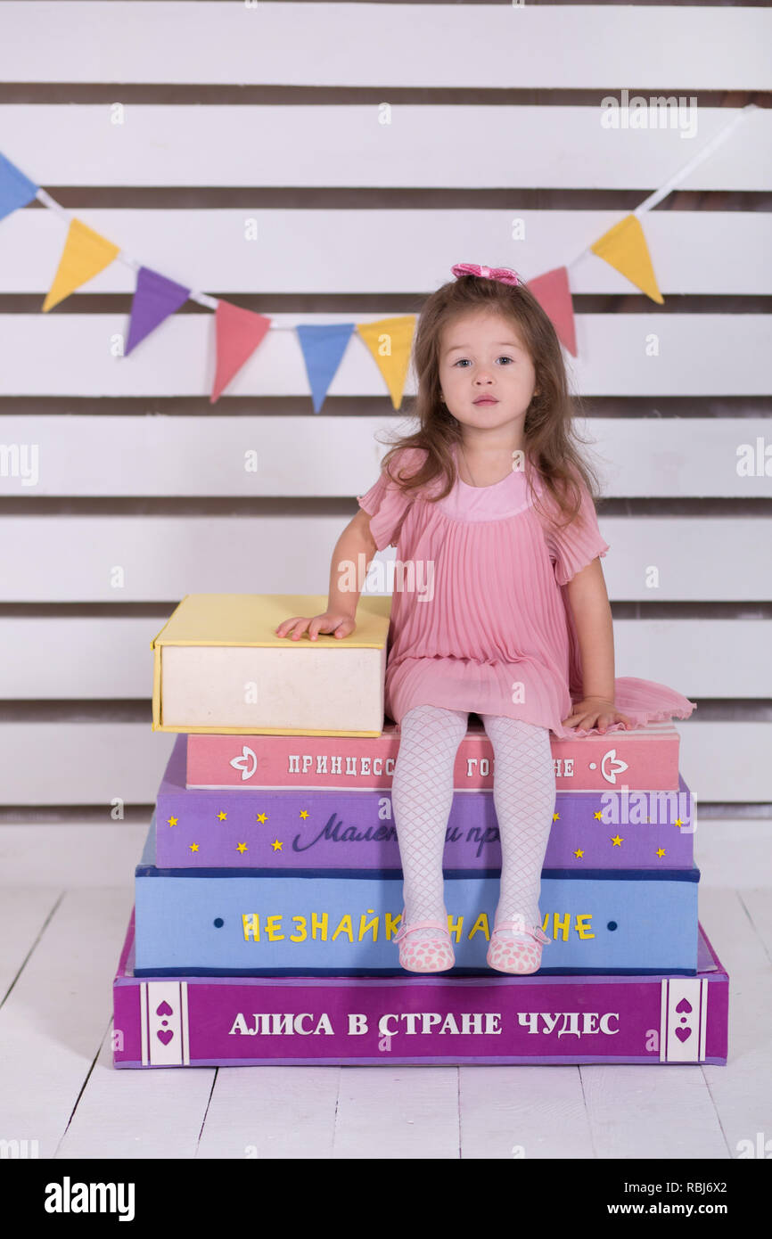 Baby doll fille en robe rose avec pout les lèvres et cheveux brunnette posant avec d'énormes livres impressionnant différentes couleurs sur prodigy maracle wonderland Banque D'Images