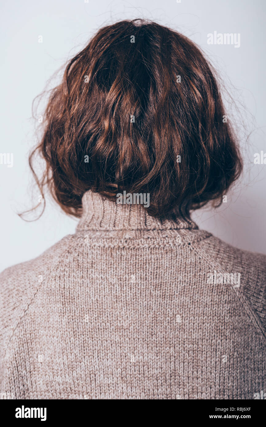 Vue arrière du jeune femme avec des cheveux bouclés habillé en laine Pull col roulé, close-up. Banque D'Images