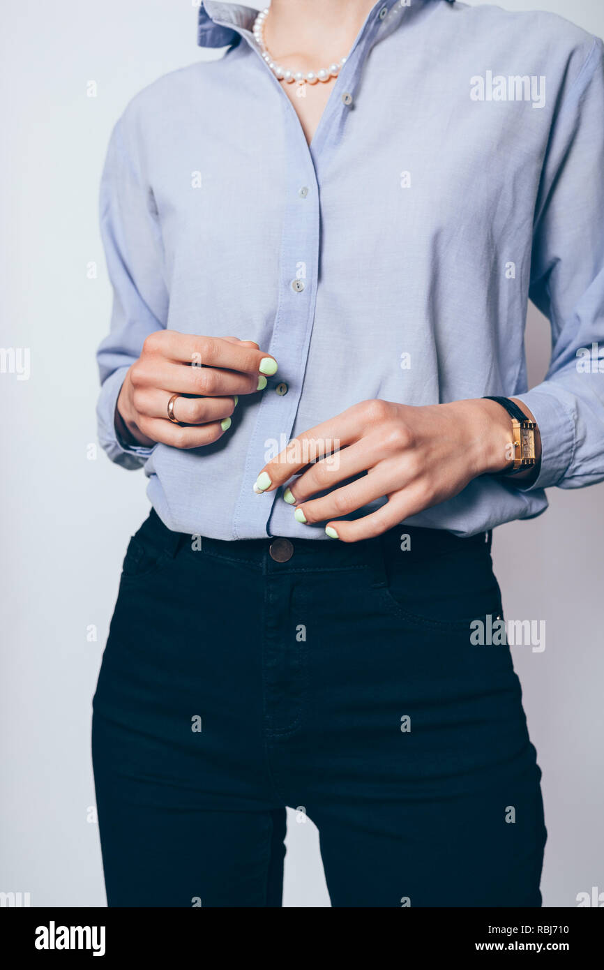 Jeune femme d'affaires élégant vêtu de noir skinny jeans, maillot bleu et collier de perles, close-up. Banque D'Images