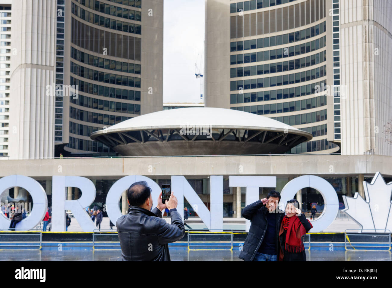 Un couple d'Asie pour leur photo devant le Toronto signer au Nathan Phillips Square, Toronto, Canada Banque D'Images