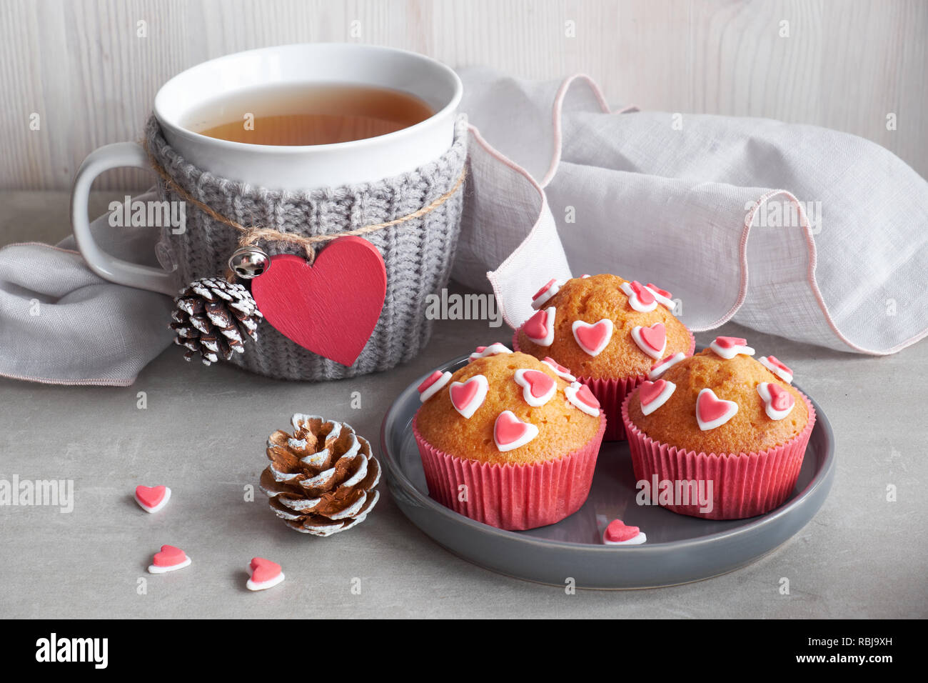 Décoré avec des coeurs muffins de sucre et une tasse avec cœur rouge sur fond gris clair. Saint Valentin ou anniversaire hiver concept. Banque D'Images