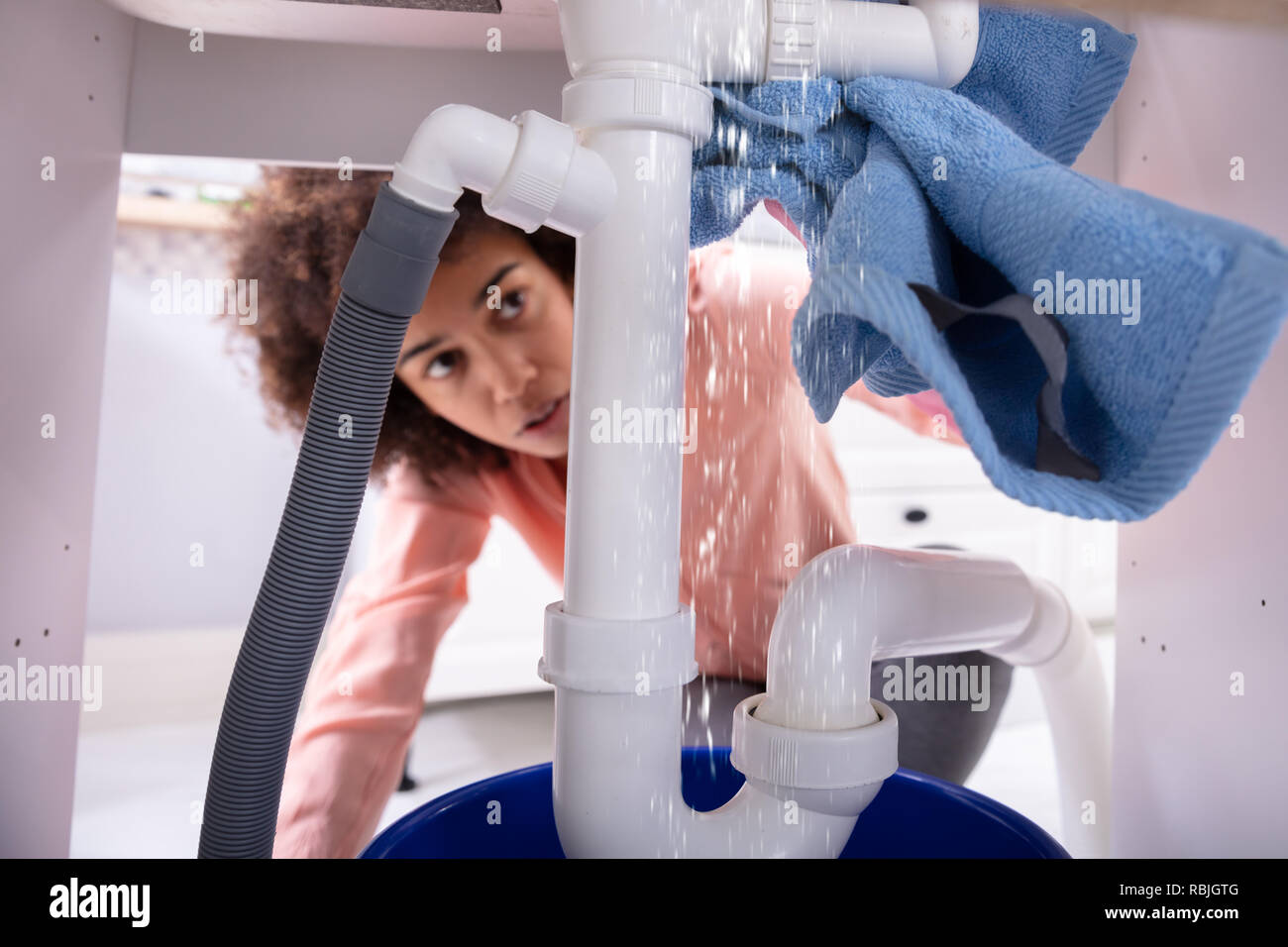 Close-up of a Young Woman Using Soft Blue Napkin Sous la fuite de tuyau évier blanc Banque D'Images