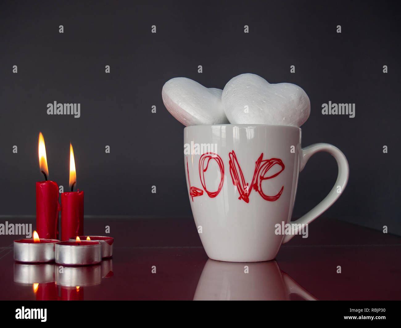 Concept d'amour avec la vie Toujours allumé des bougies rouges et deux poliespan coeurs dans une tasse petit-déjeuner avec le mot amour Banque D'Images