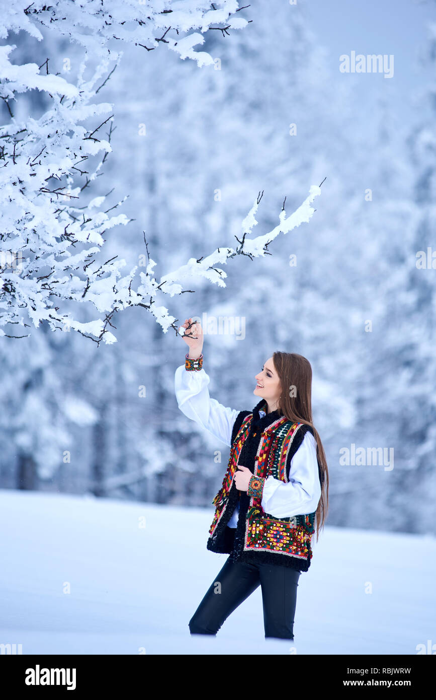 Belle jeune fille aux cheveux long en blanc et chemisier brodé veste multicolore à l'extérieur sur journée d'hiver sur Paysage de neige fond. W traditionnels Banque D'Images