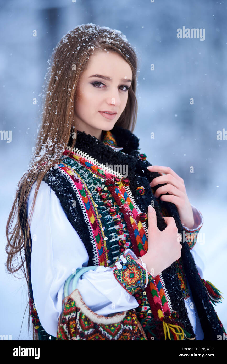 Portrait de la belle femme aux cheveux long chemisier brodé en blanc et veste multicolore à l'extérieur sur journée d'hiver sur Paysage de neige fond. Tradit Banque D'Images