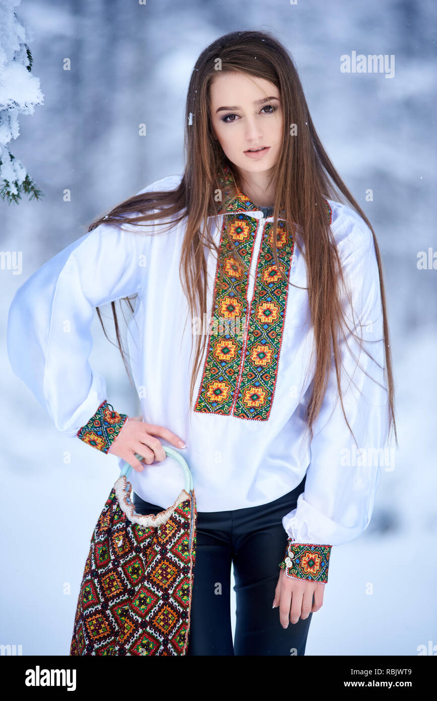 Les jeunes à la mode attrayant de long-haired woman en jeans et chemisier blanc brodé traditionnelle ukrainienne holding , sac avec embroid multicolores Banque D'Images