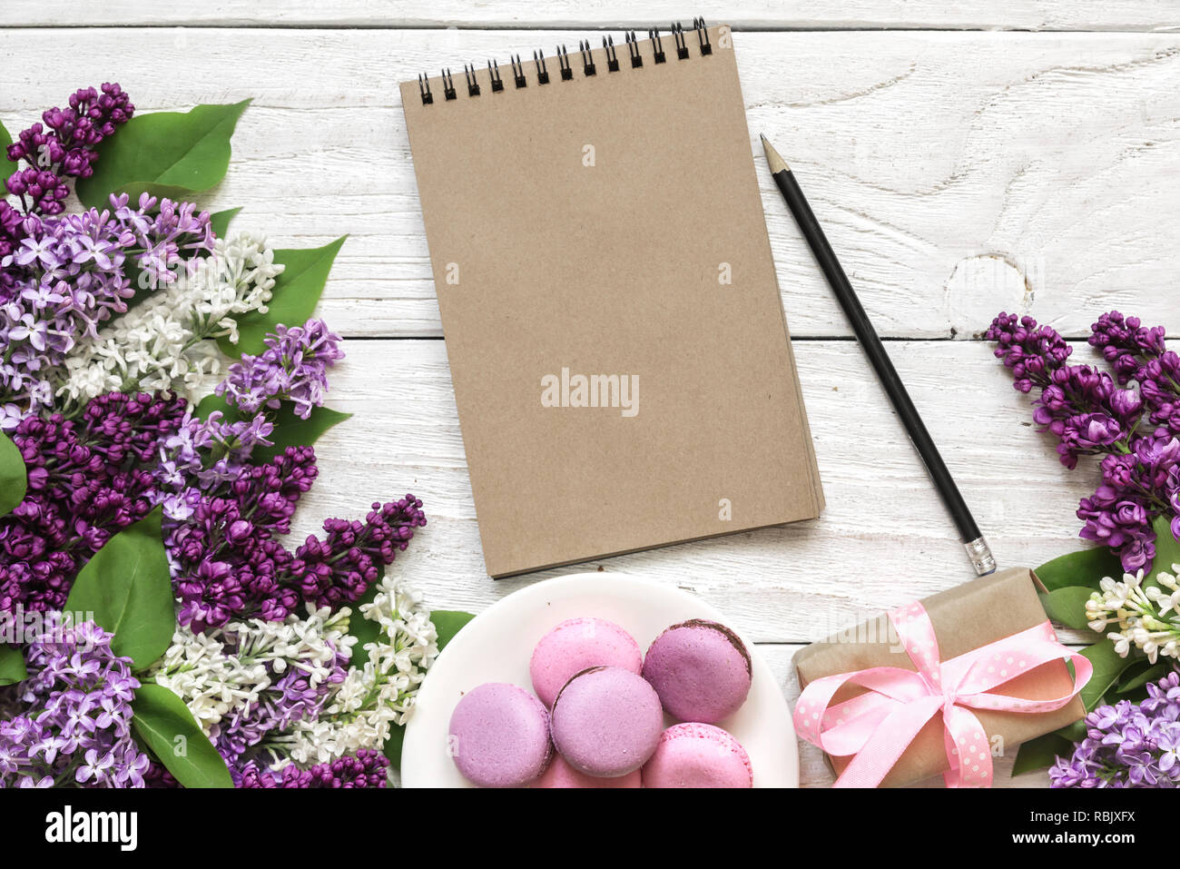 Mise en page créative faite avec des fleurs lilas, macarons, boîte cadeau et chèque en blanc sur l'ordinateur portable branché en bois blanc arrière-plan. Télévision lay. Vue de dessus du châssis. organisation mariage. Banque D'Images