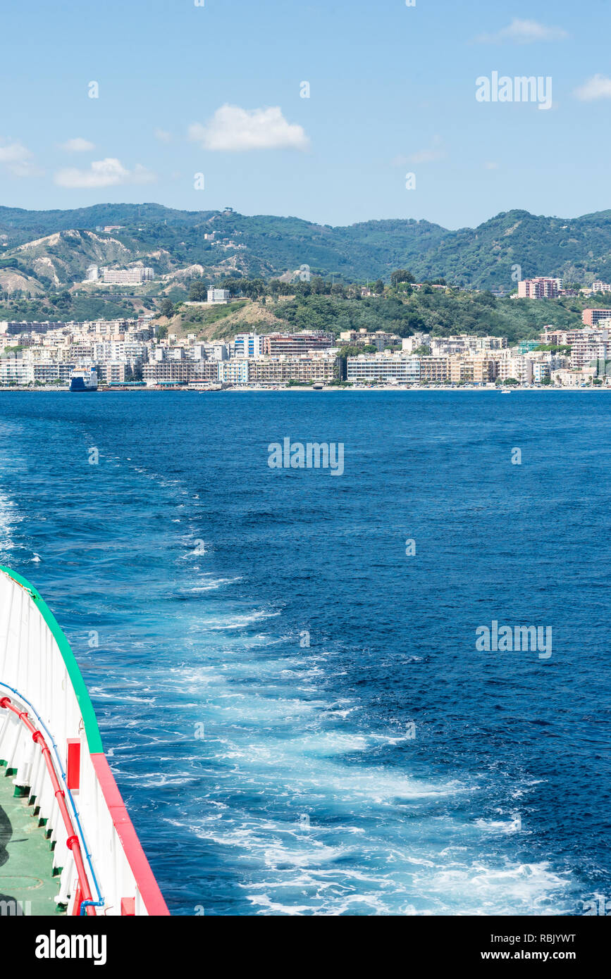 Vue sur la mer de l'arrière d'un car-ferry à travers le détroit de Messine et à l'arrière-plan la ville de Messine. Vue verticale Banque D'Images