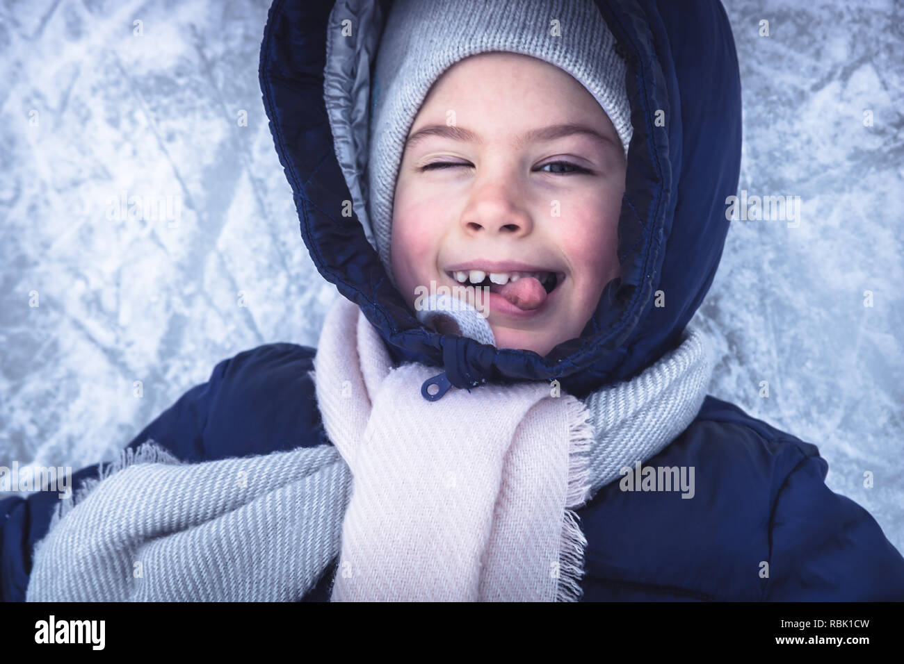 Portrait de l'enfant gai d'hiver sur la neige fond de glace s'amusant on snowy patinoire pendant les vacances d'hiver Banque D'Images
