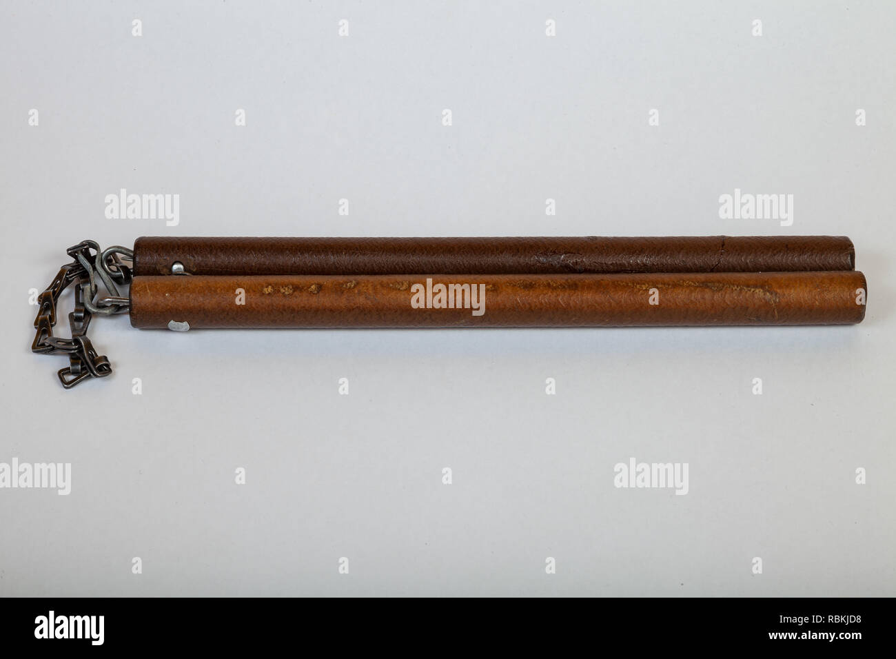 Gros plan sur vintage brown nunchak en bois reliés par une chaîne de fer, qui se trouvent à l'horizontale sur un fond isolé blanc Banque D'Images