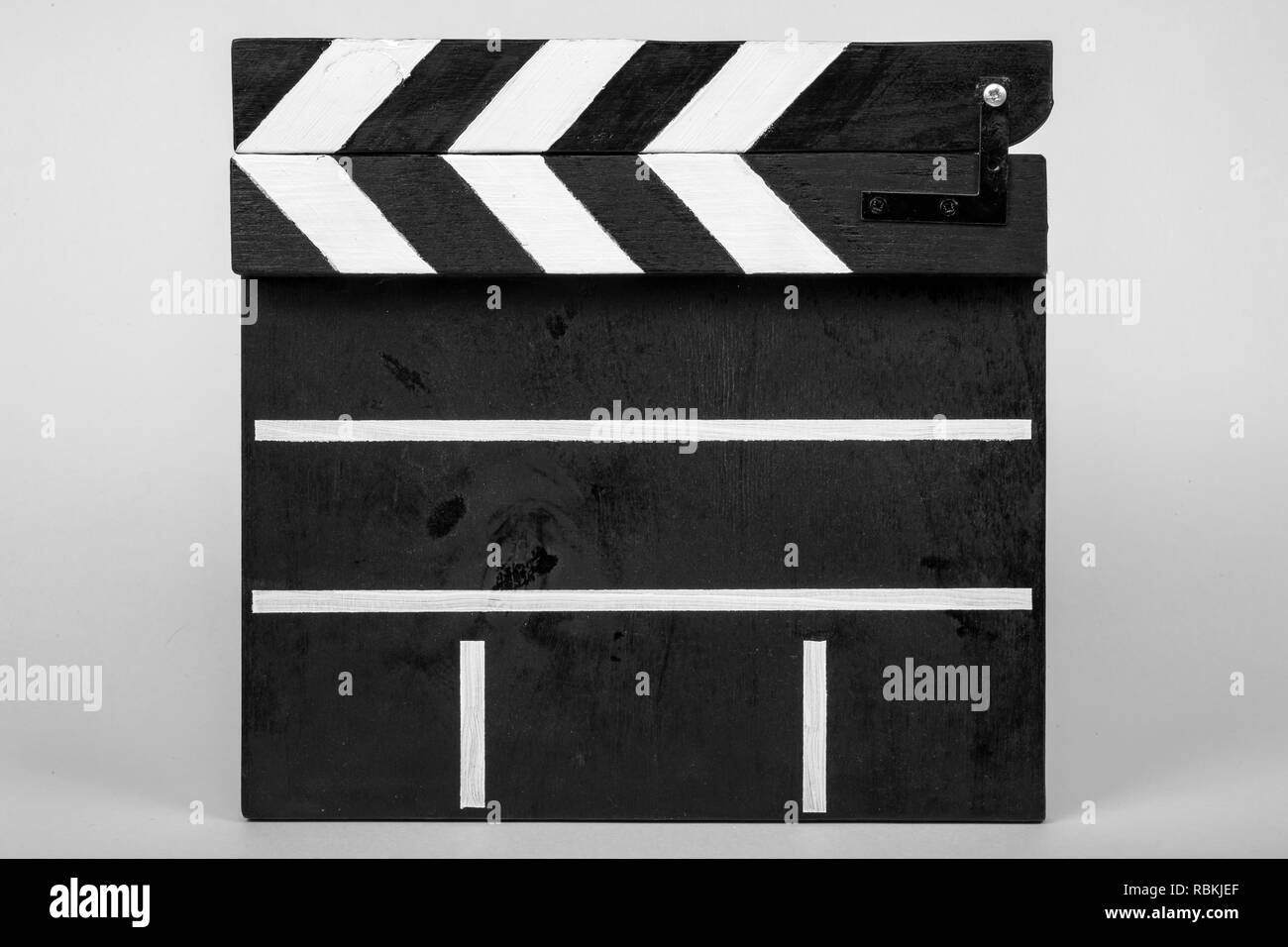 Claquoir pour indiquer le début d'un film ou un clip vidéo fait de bois et peint en noir et blanc avec rayures dans la forme fermée sur un livre blanc isola Banque D'Images