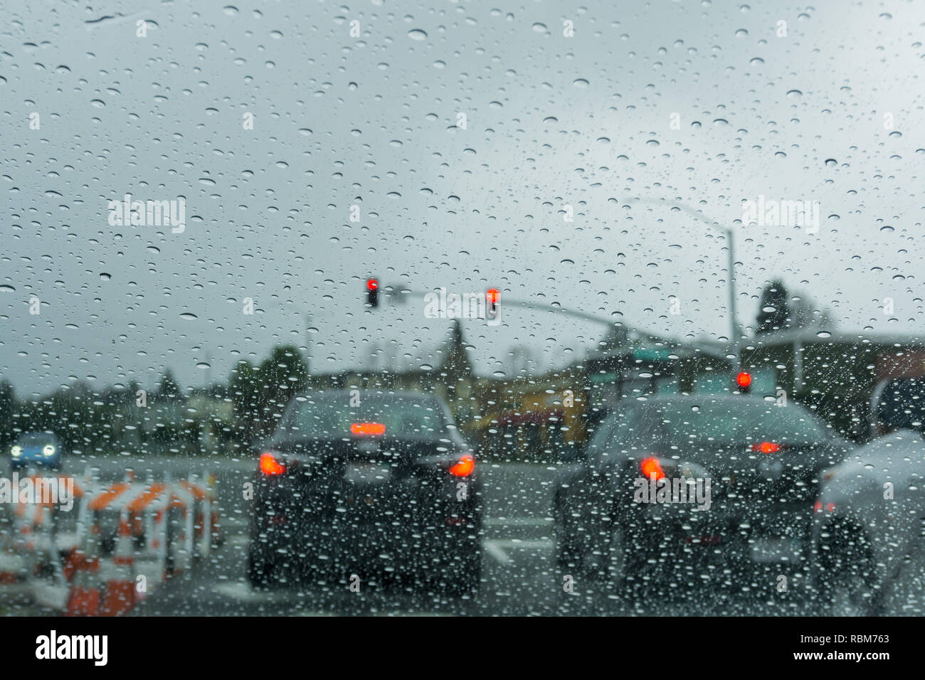 Gouttes de pluie sur le pare-brise un jour de pluie, feu arrière-plan, Californie Banque D'Images