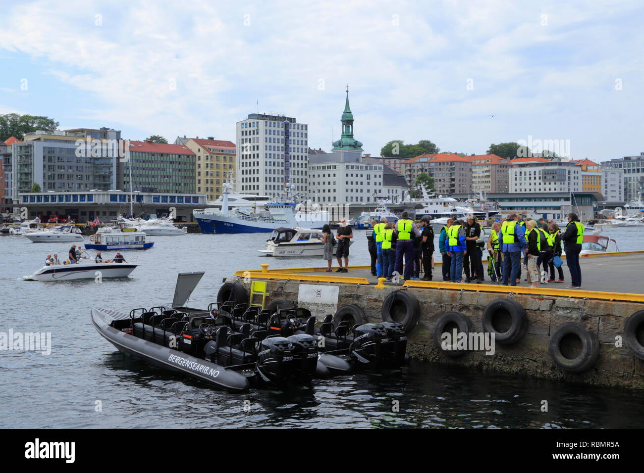 Un groupe de personnes mis sur les gilets et préparez-vous à prendre un bateau pneumatique rigide (RIB) Excursion en bateau du quai de port de Bergen, Norvège. Banque D'Images