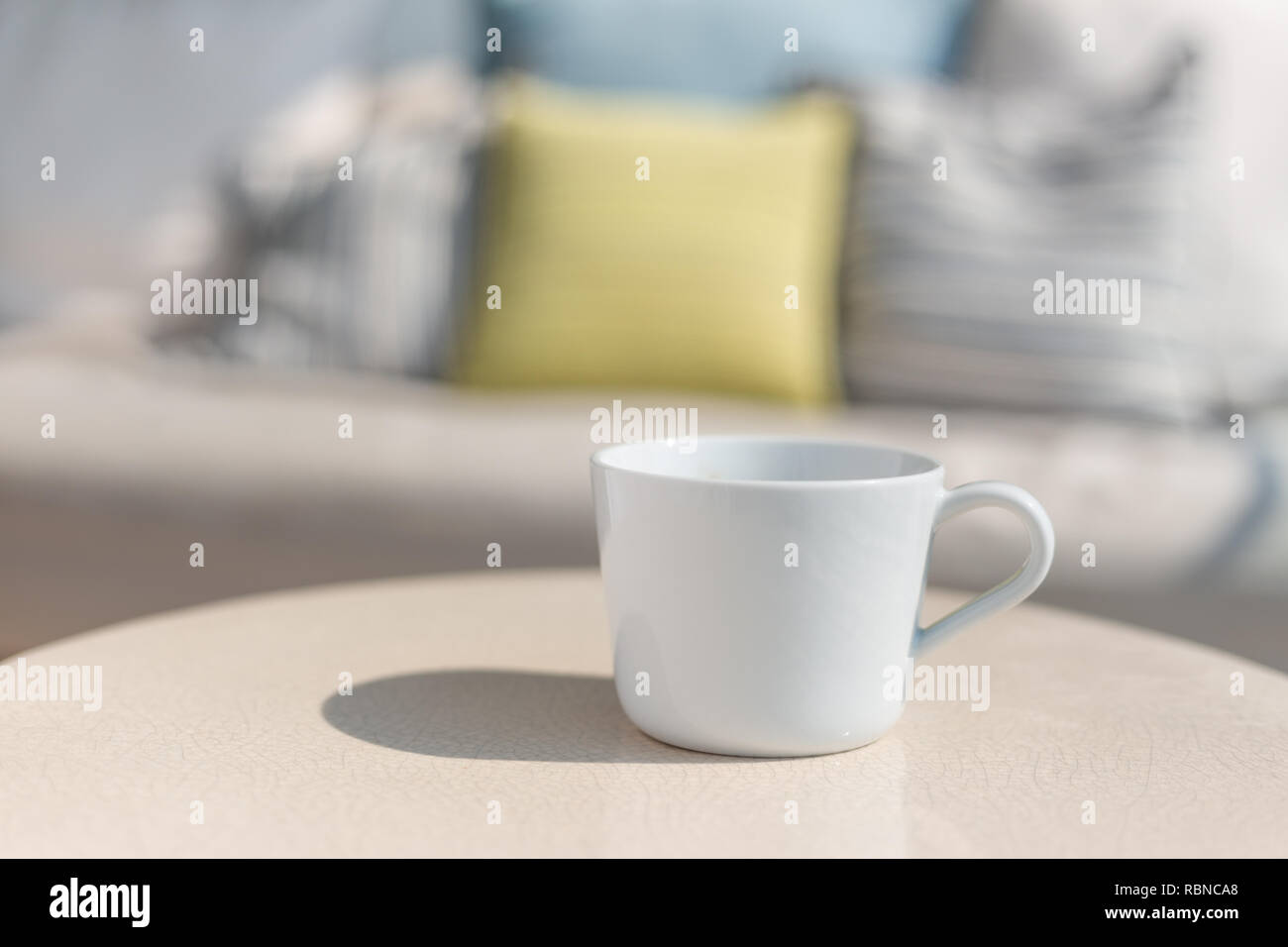 Tasse à café en céramique blanche sur table en céramique blanche, extérieur aux beaux jours avec l'ombre de la coupe sur la table Banque D'Images