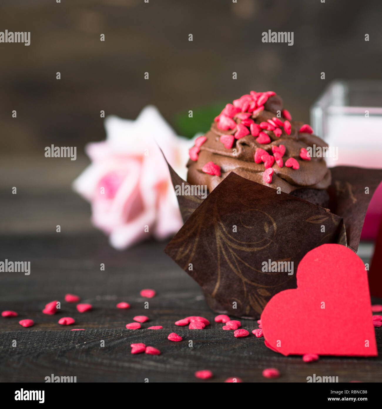 Petit gâteau au chocolat avec crème fouettée, parsemé de coeurs rouges. La cuisson des aliments sucrés pour la Saint-Valentin Banque D'Images